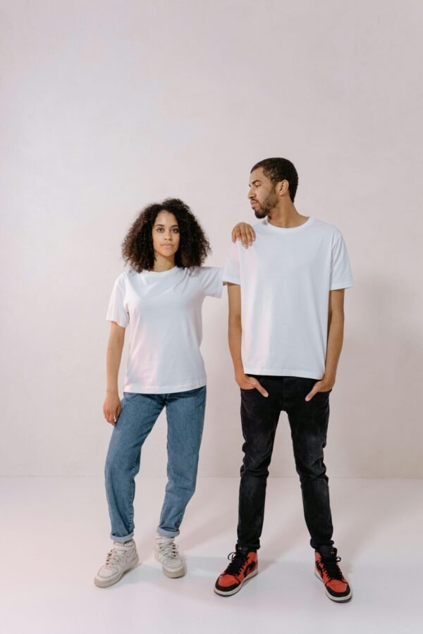 Two young adults posing in casual blank t-shirts, holding a relaxed and confident stance.